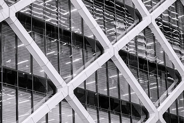 Modern skyscraper exterior featuring a prominent white diagonal structural lattice over reflective glass window panels.